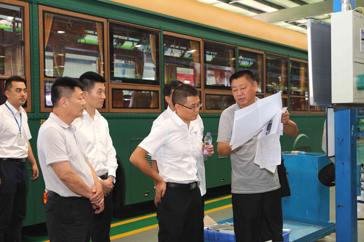 新能源汽車生產(chǎn)現(xiàn)場，領導們對汽車性能與參數(shù)作深入咨詢